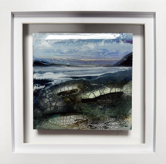 A framed landscape art print featuring a textured, cracked surface with blue, gray, and green tones, set in a wide white frame.